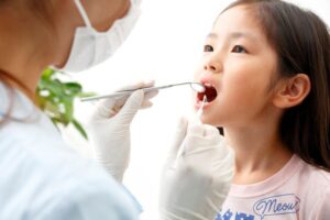 女の子の口内をチェックする歯科スタッフ
